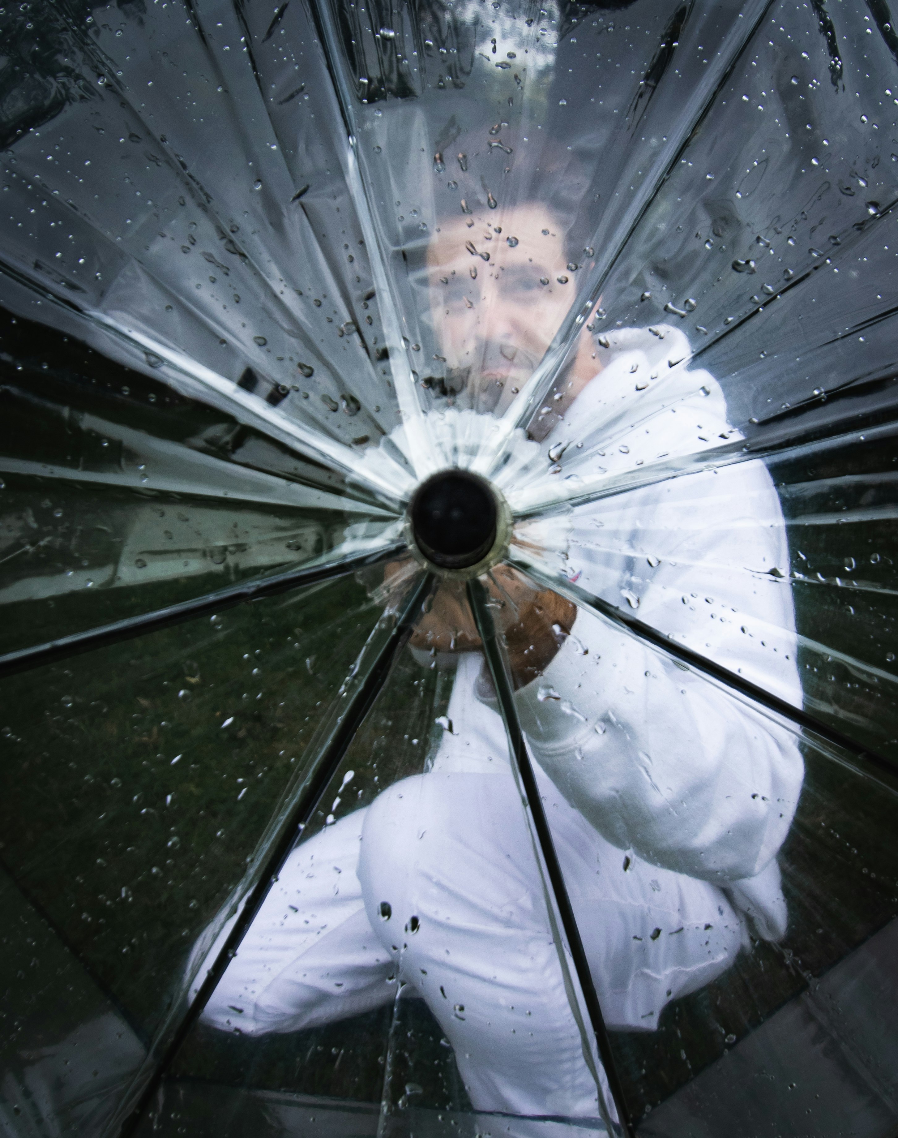 man wearing white clothes holding transparent umbrella